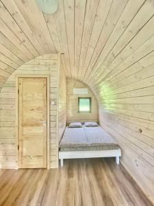 帕卢舍Palūšės Kempingas (nameliai)的一间小卧室,配有一张位于木制房间内的床