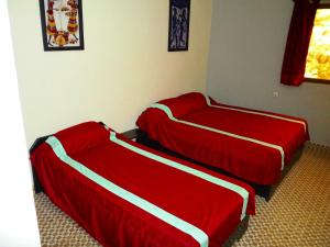 瓦加杜古卡瓦纳酒店的配有红色和白色床单的客房内的两张床