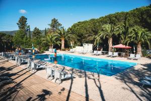 拉科纳Casa Dei Prati Camping Village的一个带椅子和棕榈树的大型游泳池