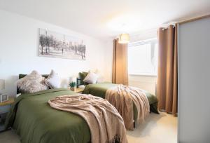 艾尔斯伯里Virexxa Aylesbury Centre - Deluxe Suite - 3Bed House with Free Parking的一间卧室设有两张绿色的床和窗户