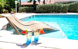 威利布罗德Kas Amigu accomodations的游泳池畔的桌子上放着两杯饮料