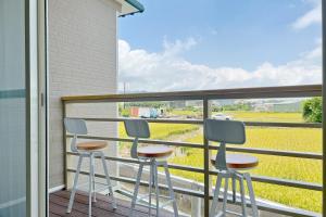 公馆喫茶居 茶蔬食主題民宿 Chih Cha Jyu的阳台设有三张凳子,享有田野美景