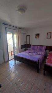乌尔齐尼Ema Apartments的一间卧室配有一张带紫色床单的床和窗户。