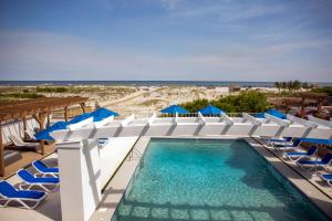 威尔伍德克拉斯特Mahalo Diamond Beach Resort的一个带椅子和蓝伞的游泳池