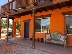 卡纳布Oranch House, Studio & Wilderness的一座橙色的房子,外面有长凳