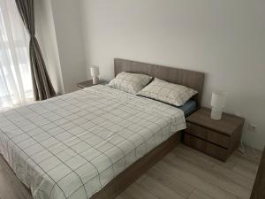 布加勒斯特Moghioros Park Residence Apartment的一间卧室配有一张带2个床头柜和2盏灯的床。