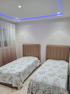 纳祖尔Appartement a Nador的卧室内的两张床,享有蓝色的灯光