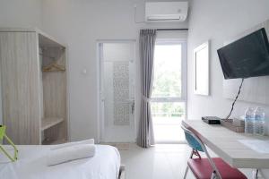 SukaramiUrbanview Hotel Bari Syariah Palembang By RedDoorz的白色的客房设有床、书桌和窗户。