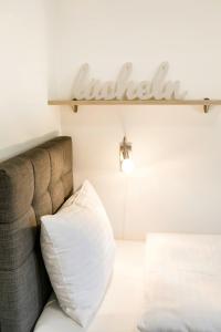 米特尔巴赫R&R Residenzen Ferienwohnungen的一张带白色枕头的沙发,墙上有标志