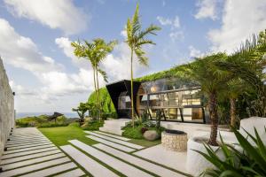 库塔Airship Bali by Alex Villas的前面有棕榈树的房子