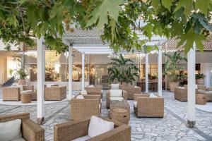 卡拉马基Leptos Panorama Hotel的大堂设有藤椅和桌子,树木繁茂