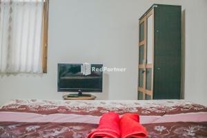 Villa Mawar Adinda Kuningan Syariah RedPartner的床上一双红色的拖鞋,带一台电视机