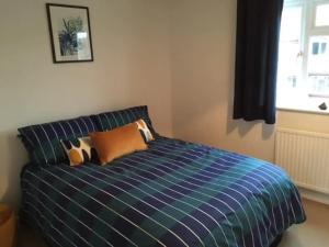 RoffeyKB21 Attractive 2 Bed House, pets/long stays with easy links to London, Brighton and Gatwick的一间卧室配有蓝色的床、枕头和窗户
