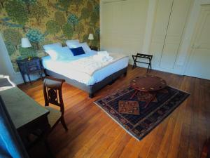 沙托鲁Maison d'hôtes de charme - Au Lys Blanc的一间卧室配有一张床、一张桌子和一张地毯。