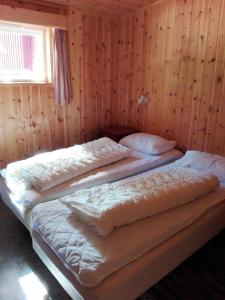 InnfjordenLensmansgarden Fjøsen的带木墙的客房内的三张床