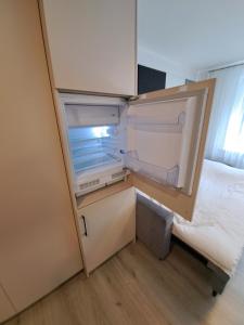 克莱佩达New cosy Karklu Apartment in Klaipeda的空的冰箱,门打开在床边