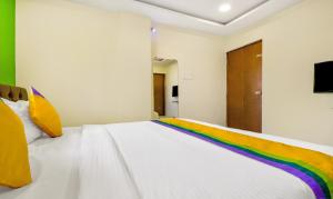 那格浦尔Itsy By Treebo - Carnival Inn的一张白色的床,上面有彩虹毯子