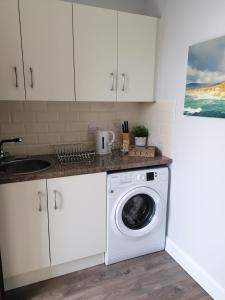 BreaghwyAtlantic way Apartment 1的厨房配有洗衣机和水槽