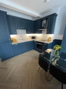利马瓦迪Roe Valley Apartments的厨房配有蓝色橱柜和玻璃桌