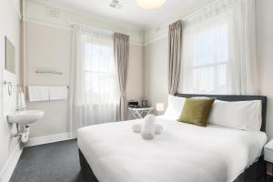温特沃斯瀑布君怡酒店的卧室配有一张白色大床,上面有泰迪熊