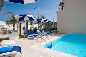 卡利亚里诺迪鲁斯酒店的一个带蓝白遮阳伞和椅子的游泳池以及一个游泳池