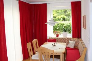 卡塞尔Das Blaue Haus - Ferienwohnung Schönherr的一间设有红色窗帘和桌子的用餐室