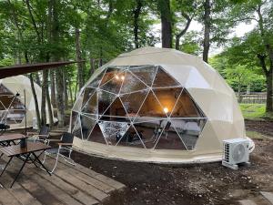 山中湖村THE DAY POST GENERAL GLAMPING VILLAGE Yamanakako的一个带桌椅的大型伊瓜纳帐篷