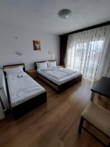 图尔达Pensiunea Daiana Residence的铺有木地板的客房内的两张床