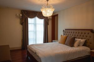 济州市ArdenHill Resort & Golf的一间卧室配有一张带吊灯的大床