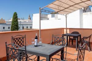 塞维利亚圣士提反门酒店的阳台上的桌椅和一瓶葡萄酒