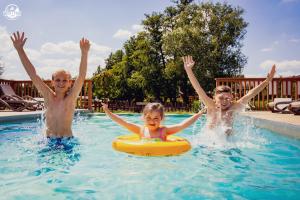 扎托尔Western Camp Resort的两个男孩和一个女孩在游泳池里