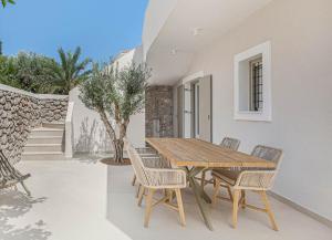 斯派赛斯Pearl House - Luxurious new beach villa in Spetses stunning view的天井上的木桌和椅子