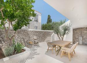 斯派赛斯Pearl House - Luxurious new beach villa in Spetses stunning view的庭院设有木桌、椅子和石墙