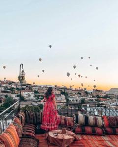 格雷梅Lord of Cappadocia Hotel的穿着红色衣服的女人站在带气球的阳台