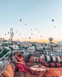 格雷梅Lord of Cappadocia Hotel的两人坐在阳台上的沙发上,阳台上配有热气球