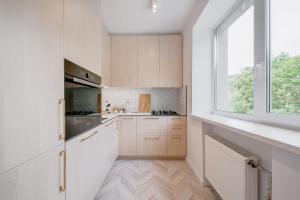 考纳斯Central Apartment in Architectural Street的厨房配有白色橱柜和窗户。