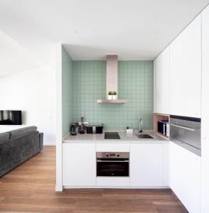 洛格罗尼奥Invino Apartments的厨房配有白色橱柜和绿色瓷砖