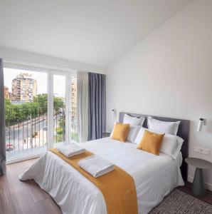 洛格罗尼奥Invino Apartments的白色的卧室设有一张大床和一个大窗户