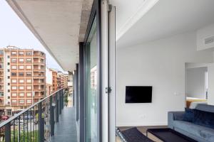 洛格罗尼奥Invino Apartments的客房设有一个带沙发和电视的阳台。