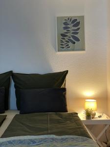 弗莱堡Mida Gästehaus的一张带绿色枕头的床和一张桌子上的台灯