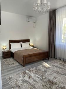 塔尔迪库尔干Апарт отель Welcome的一间卧室配有一张大床和一个吊灯。