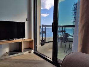 贝西奇Silver Beachfront Becici的一间带电视和滑动玻璃门的客厅