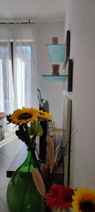 莫诺波利Serena GuestHouse的花朵花在房间内的绿色花瓶