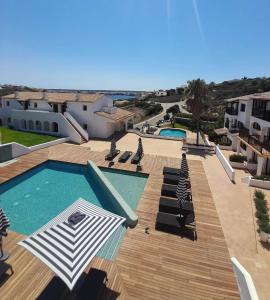 马翁Calallonga Hotel Menorca的一个带遮阳伞和椅子的游泳池以及一个游泳池