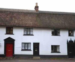 OttertonThatched Cottage, beautiful village near the sea的白色的房子,有红色的门和窗户