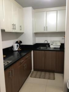 马尼拉Budget Friendly-Spacious One Bedroom Suite Opposite to Naia 3的厨房配有白色橱柜和水槽