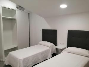 巴约讷Precioso apartamento vacaciones en zona Ramallosa的白色墙壁客房的两张床