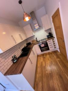 伯恩茅斯Stylish One Bedroom Central Bournemouth Flat的厨房铺有木地板,配有白色橱柜。