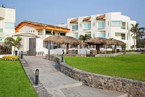 查察拉卡斯Artisan Family Hotels and Resort Collection Playa Esmeralda的公园前有草伞的建筑