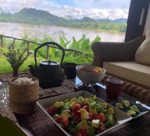 琅勃拉邦On The Mekong Resort的一张桌子,上面放着一盘食物和一碗水果